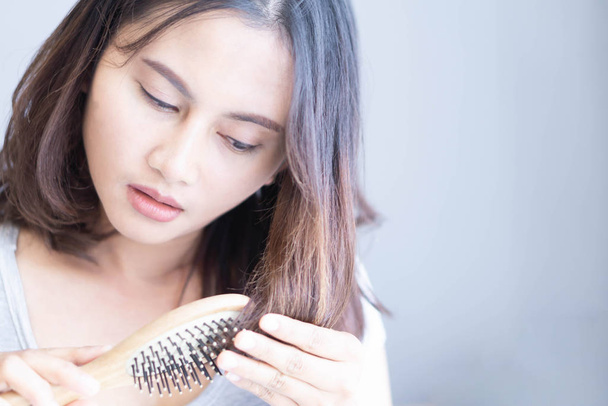 Woman hand holding comb with serious hair loss problem for health care shampoo and beauty product concept, selective focus - 写真・画像