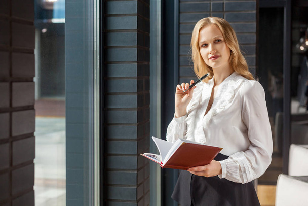 Portrait of smart devious businesswoman holding diary book for n - Photo, Image