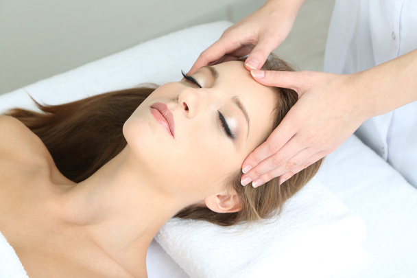 Beautiful young woman during facial massage in cosmetic salon close up - Foto, imagen