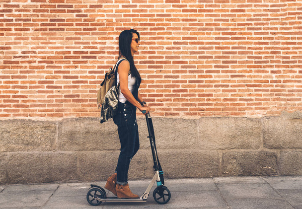 Femme cool à bord d'un scooter électrique dans la rue - Photo, image