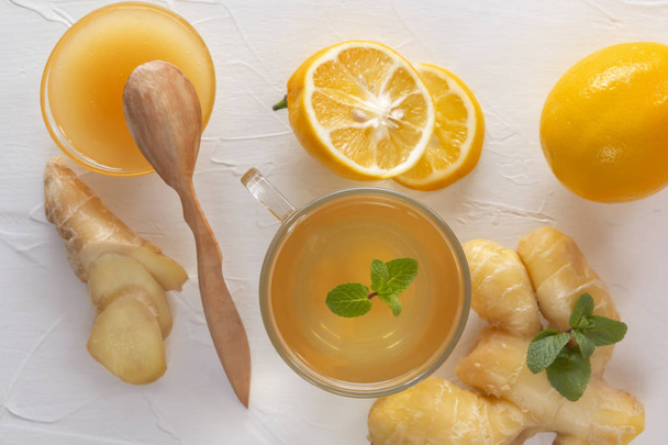 Té con jengibre, menta, limón y miel en una mesa de madera blanca. Vista superior
 - Foto, imagen