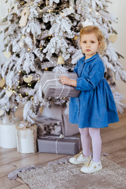 Little girl with Christmas gifts near a Christmas tree - Photo, Image