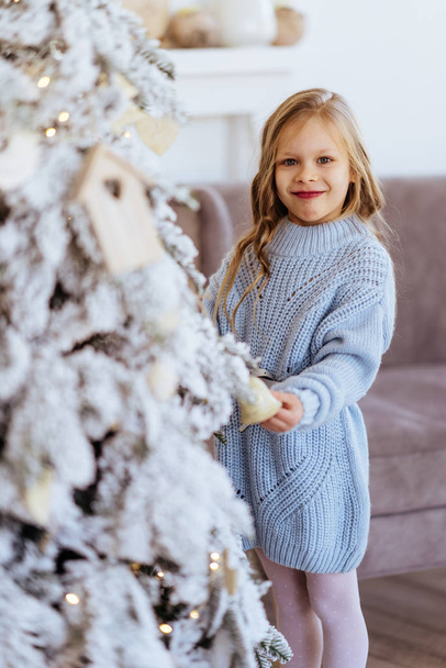 Little girl with Christmas gifts near a Christmas tree - Фото, зображення