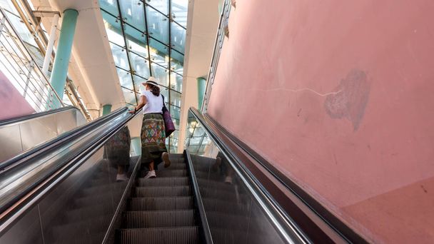 Asian woman riding up escalator in Metro station - Photo, Image