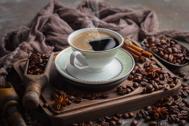 Koffie in een kopje op een achtergrond van koffiebonen, op een oude achtergrond. - Foto, afbeelding