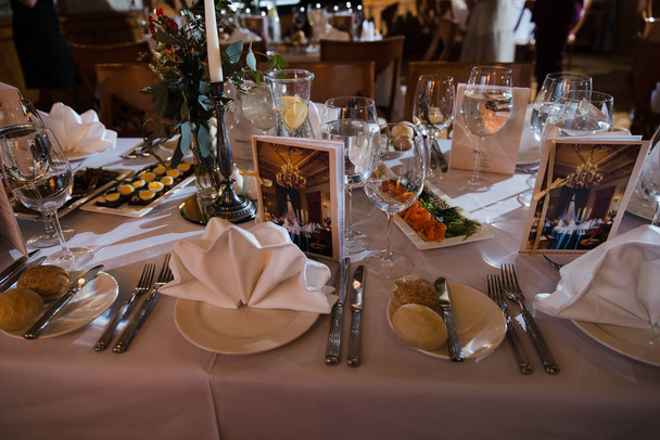 Comida servida en una mesa en un salón blanco durante una fiesta corporativa de cumpleaños en el Báltico de Europa Oriental Riga, Letonia - colores crema y biege - Canapé, aperitivos y bebidas ligeras
 - Foto, imagen