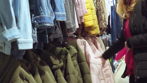 dziewczyna wybiera ubrania w sklepie - Materiał filmowy, wideo