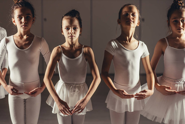 group of little caucasian ballerinas stand in row and practice ballet - Photo, Image