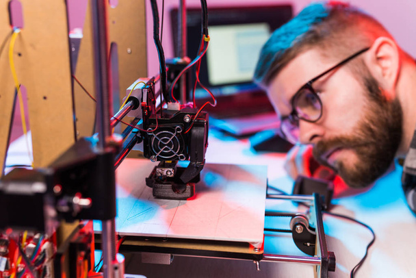 Jovem engenheiro de design masculino usando uma impressora 3D no laboratório e estudando um protótipo de produto, tecnologia e conceito de inovação
 - Foto, Imagem