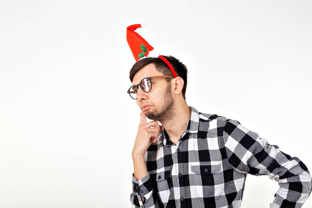Концепция праздников и подарков - Веселый эмоциональный человек в рождественской шляпе на белом фоне с копирайтом
 - Фото, изображение