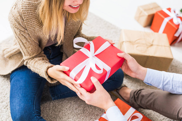Christmas and holidays concept - Close-up of young happy couple opening gifts at home. - Foto, Imagen
