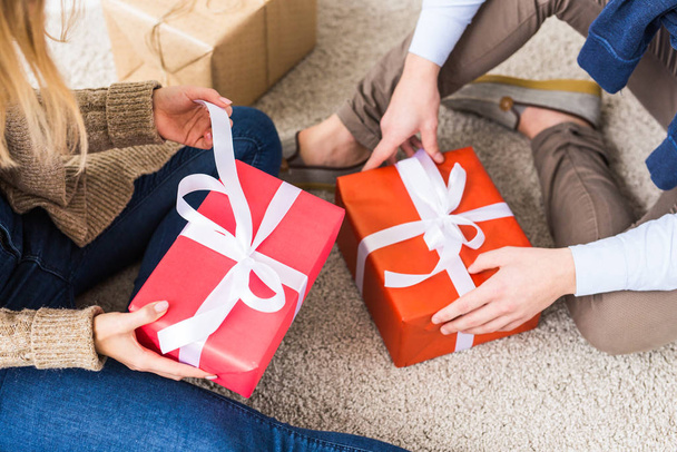 Concepto de Navidad y vacaciones - Primer plano de la joven pareja feliz abriendo regalos en casa
. - Foto, Imagen