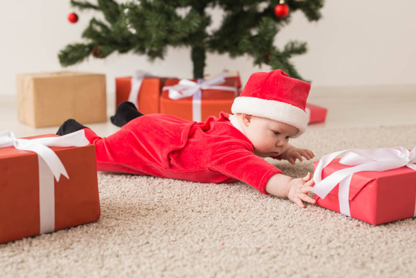 Mignon bébé fille portant santa claus costume rampant sur le sol sur l'arbre de Noël. Période des fêtes
. - Photo, image