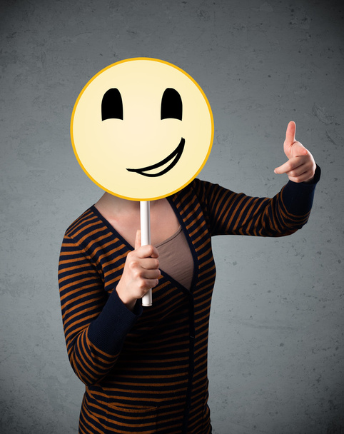 Young woman holding a smiley face emoticon - Photo, Image