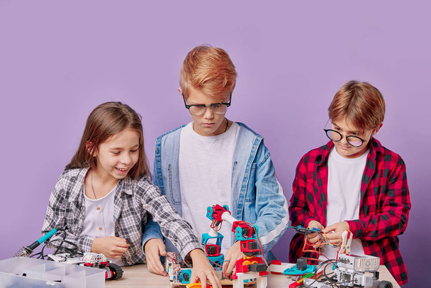 children and a lot of small robots with wires on table - Фото, изображение