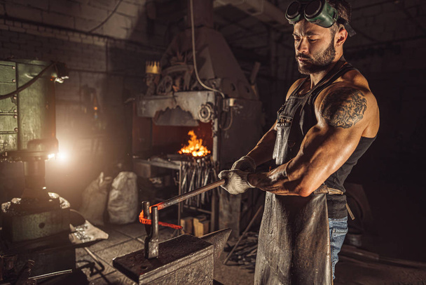 serious and confident blacksmith shaping metal - Fotoğraf, Görsel