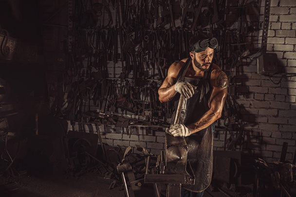 side view on young blacksmith tired doing work - 写真・画像