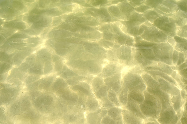 Ελαφριά άμμος κάτω από το θαλασσινό νερό στην παραλία. Υπέροχο κρυστάλλινο νερό. Υφαντική υφή άμμου κάτω από νερό - Φωτογραφία, εικόνα