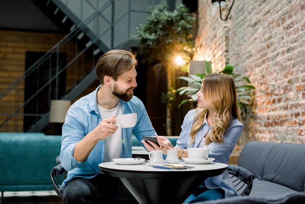Happy couple or friends flirting talking and drinking coffe in a restaurant or cafe or waiting room - Foto, imagen