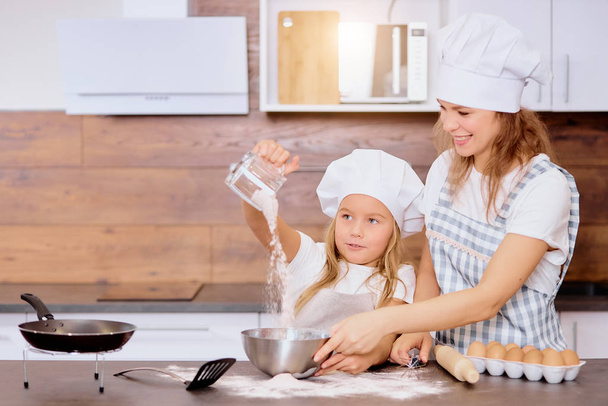 Happy caucasian mother and daughter baking together in the kitchen - Foto, Bild