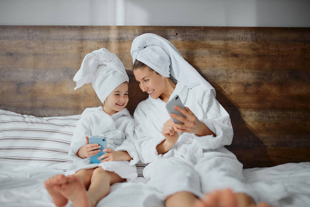 young caucasian mother with daughter use smartphone - Photo, Image