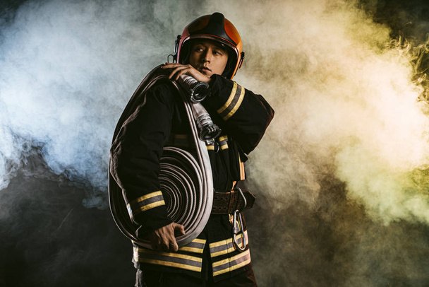 handsome firefighter isolated in smoky space - Fotó, kép