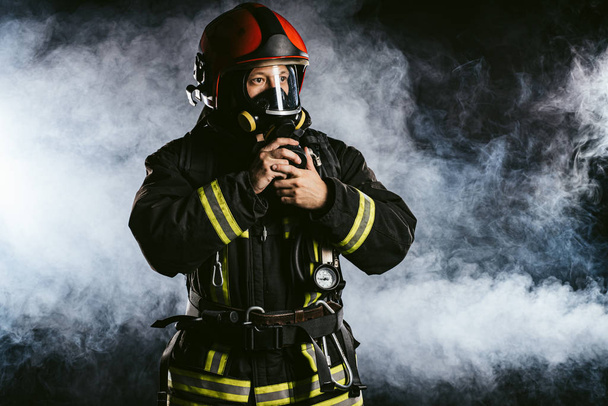 kavkazský hasič v uniformě stojí v kouři - Fotografie, Obrázek