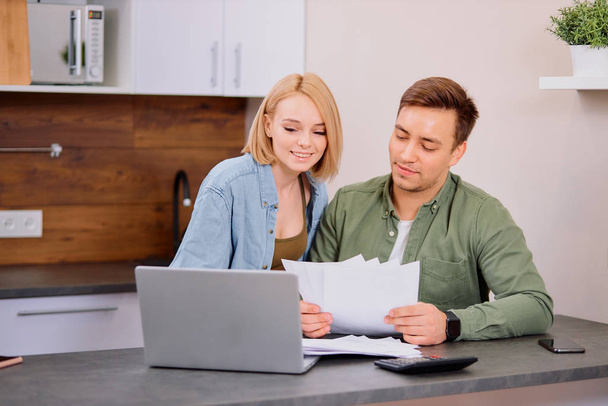 Focused young caucasian couple checking analyzing utilities bills at home - Фото, изображение