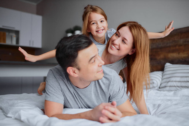 Loving cute parents with their cute little kid girl on bed - Zdjęcie, obraz