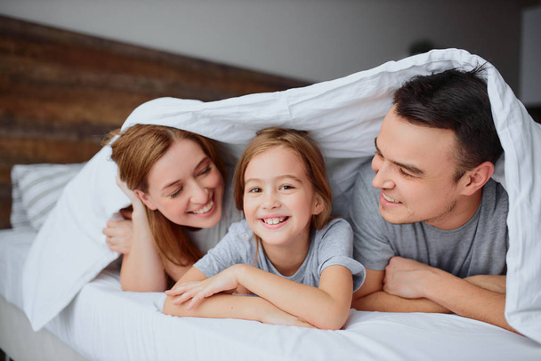 portrait cheerful positive family under blanket at home - Fotó, kép