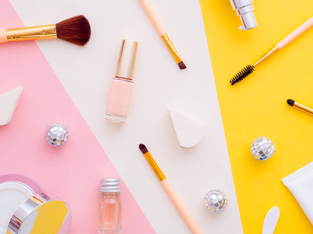 Γυναικείος χώρος εργασίας blogger ομορφιάς μόδας. Εργαλεία μακιγιάζ καλλυντικά, λοσιόν, μπουκάλια αφρόλουτρο, σφουγγάρι, κρέμες που απομονώνονται σε πολύχρωμο ροζ κίτρινο λευκό χαρτί αντίγραφο χώρο φόντο. Άνω όψη - Φωτογραφία, εικόνα