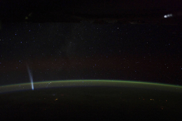 NASAによって撮影されたこの夜の画像では、ラブジョイ彗星が地球の地平線の近くで見えます。この画像の構成要素は - 写真・画像