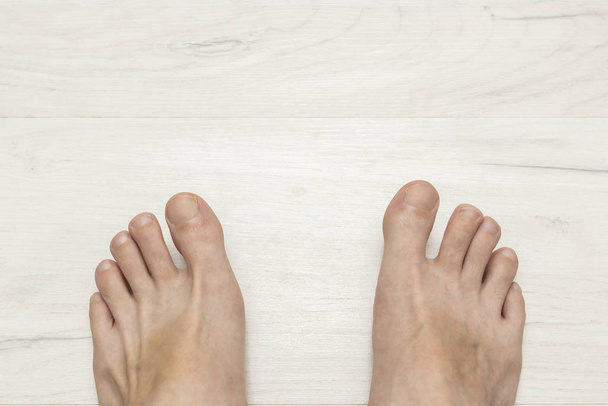 Λευκός άντρας με γυμνά πόδια σε ξύλινο πάτωμα - Φωτογραφία, εικόνα