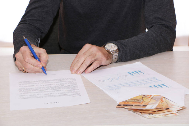 A businessman signs a contract and gives out cash. - Fotó, kép