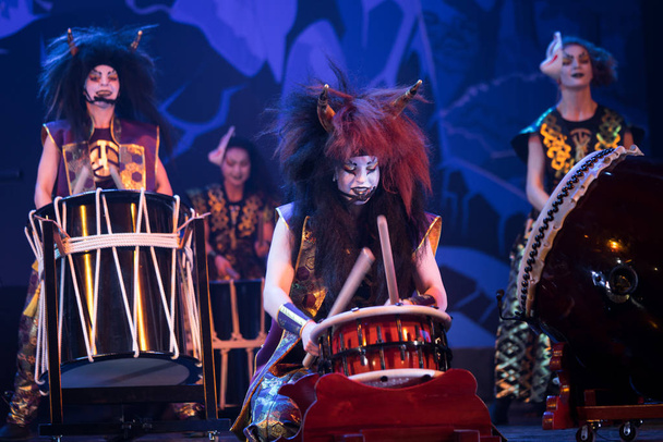 Performance tradizionale giapponese. I batteristi Taiko in parrucche e maschere demoniache si esibiscono sul palco con tamburo su sfondo scuro. Demoni della mitologia giapponese
. - Foto, immagini