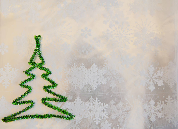 espacio de copia. árbol de Navidad verde de oropel sobre copos de nieve fondo blanco. clima invernal nevado. Feliz navidad. tiempo de felicitación de Navidad. Deja que nieve. decorar el árbol. tarjeta de felicitación de año nuevo
 - Foto, Imagen