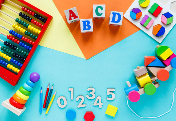 Wooden kids toys on colourful paper. Educational toys blocks, pyramid, pencils, numbers, train. Toys for kindergarten, preschool or daycare. Copy space for text. Top view - Foto, Imagem