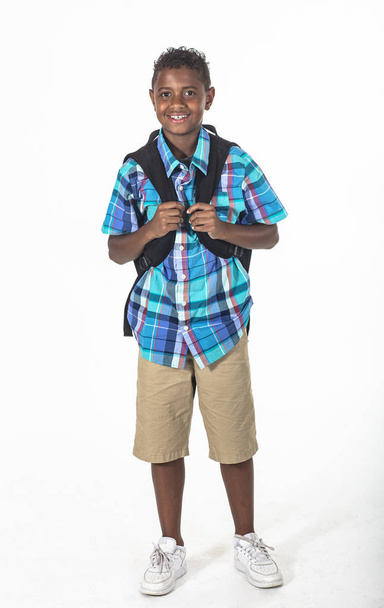 Sorridente ragazzo scolastico afroamericano isolato su sfondo bianco. Indossare uno zaino e una camicia plaid e pronto per andare a scuola. Vista frontale - Foto, immagini