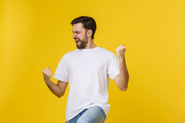 Happy young man with arms up isolated on a yellow background. - Photo, Image