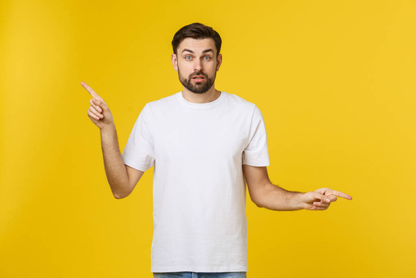 Handsome man over isolated yellow wall frustrated and pointing to the front. - Foto, afbeelding
