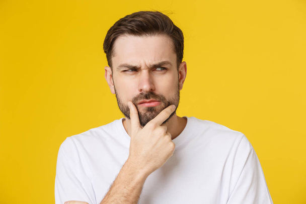 Thinking man isolated on yellow background. Closeup portrait of a casual young pensive man looking up at copyspace. Caucasian male model. - Photo, Image