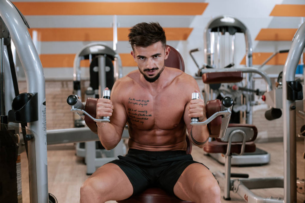 Jeune homme musclé torse nu faisant l'exercice de presse de banc d'haltère à la salle de gym
 - Photo, image