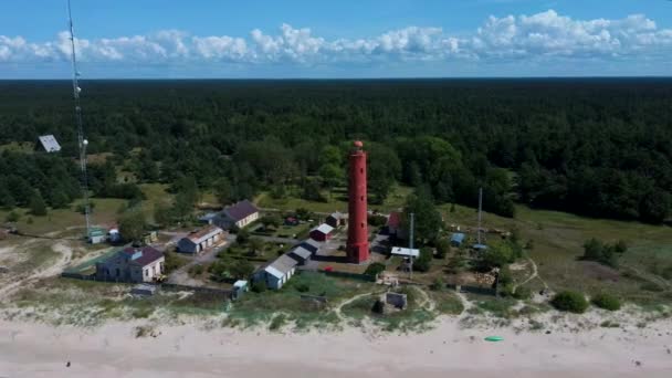 Aerial Dron Shot Akmenrags Faro en la costa letona del Mar Báltico, situado al sur de la ciudad turística de Pavilosta. Día soleado de verano. La torre actual fue construida en 1921
 - Metraje, vídeo