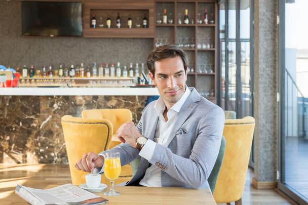 Handsome young businessman drinks coffee in hotel cafe - Fotoğraf, Görsel