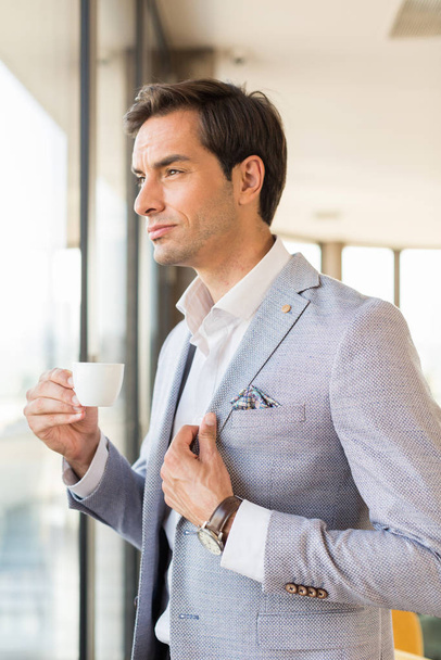 Handsome young businessman drinks coffee in front of the hotel w - Fotó, kép