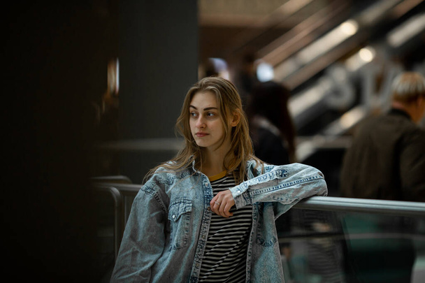 Teenager. Young pretty white caucasian teenage girl with long hair with problem skin and long hair in a shopping center near the railing. - Fotó, kép