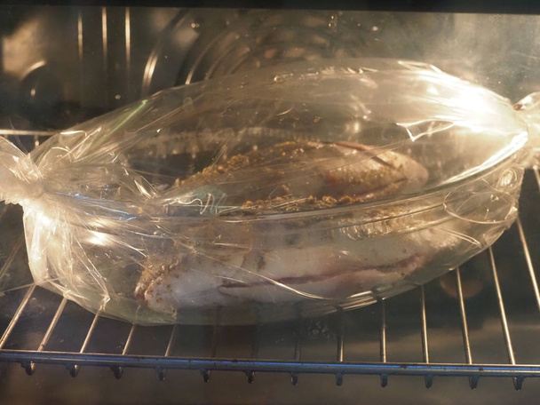 Dorado fish sprinkled with spices for cooking in glassware and in the baking sleeve - 写真・画像