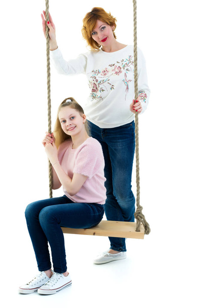 Mom and daughter swinging on a swing. - 写真・画像