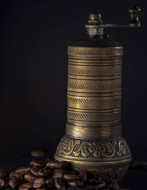 Brass coffee grinder on a black background with roasted coffee beans. Isolated on black background. - Foto, immagini