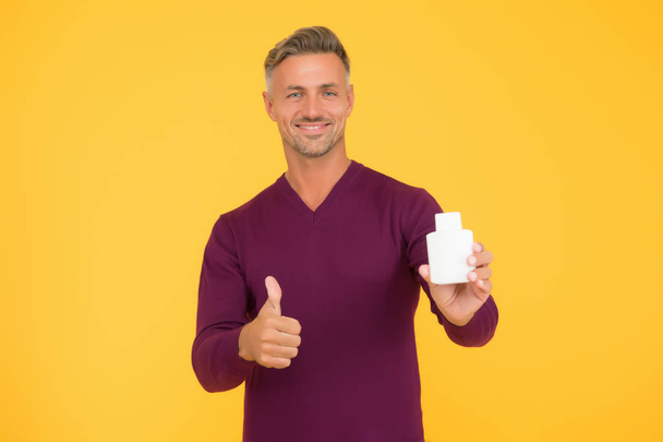 Body care. Presenting product. Mature man pointing at bottle. Favorite lotion after shaving. Worth to try. Cosmetics for men. Beauty product. Handsome well groomed healthy guy recommend product - Fotoğraf, Görsel